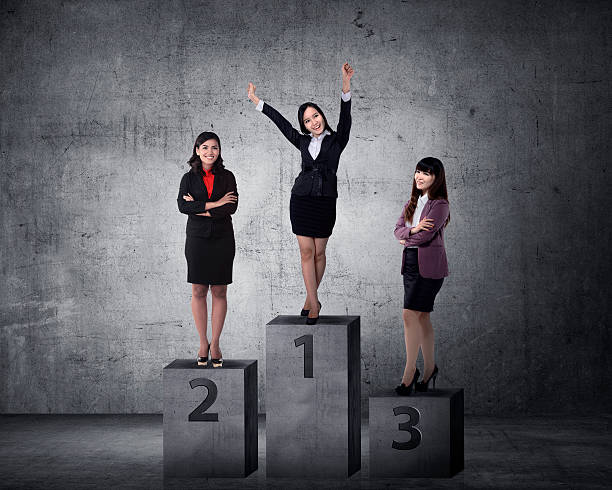 3 female Asian students standing on a tiered podium in positions 1, 2, and 3.