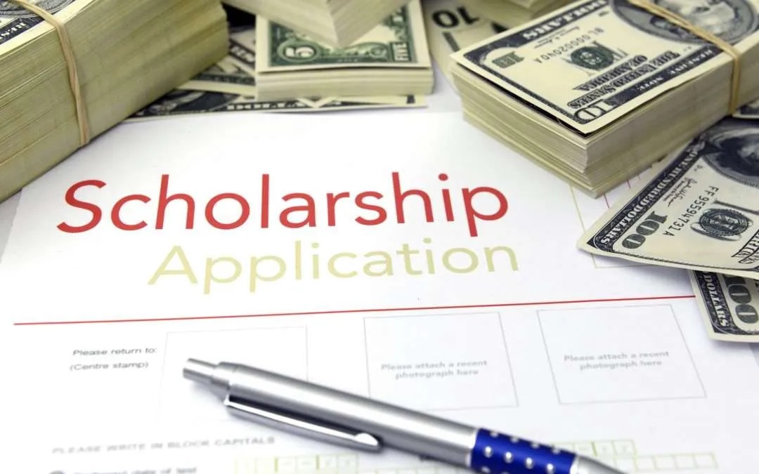 scholarship application with a pen and a stack of money behind it